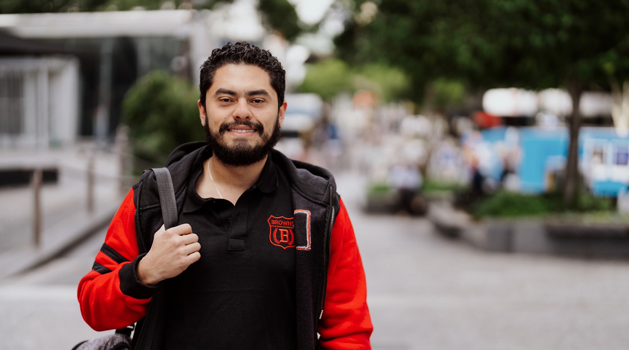 Male student with a backpack on his shoulder smiling at the camera in Brisbane, Queensland Australia. 