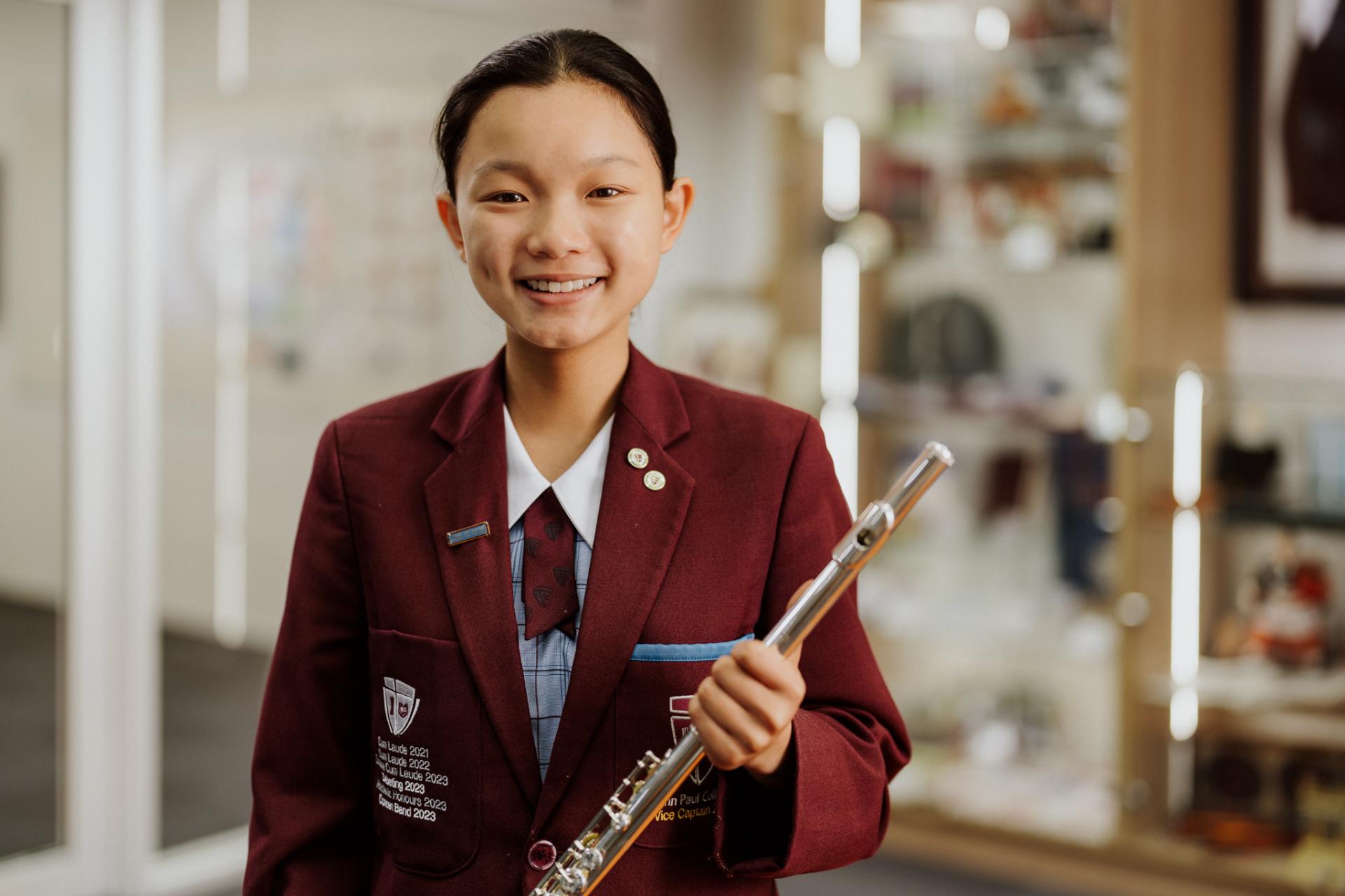 Female student standing with a flute in her hand.