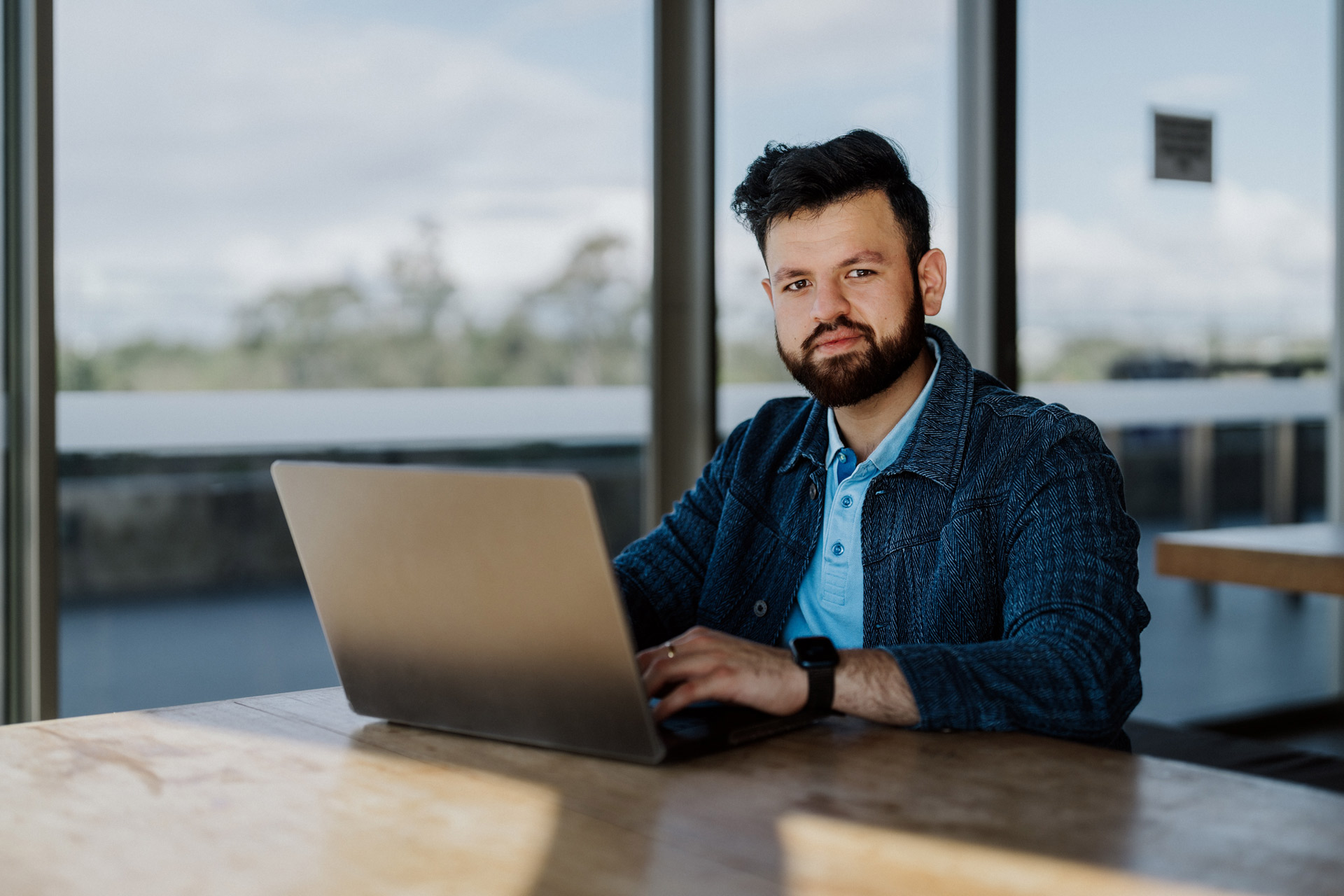 Male student sitting at a desk behind a laptop. 