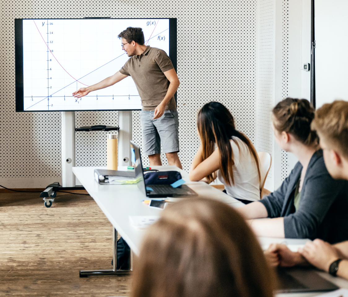 Male lecturer showing students a graph.